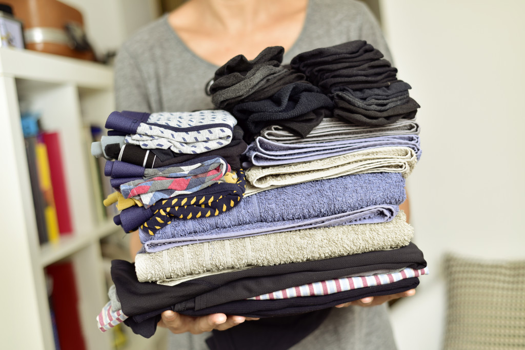 closeup of a young man carrying a pile of different folded clothes