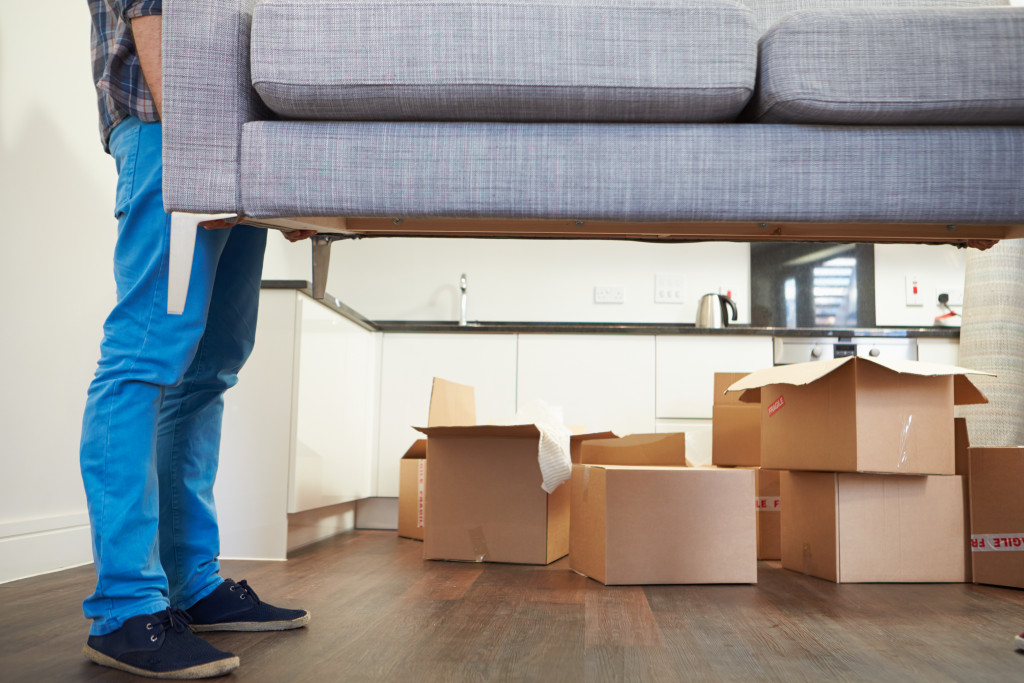 a man carrying a sofa with boxes in the background