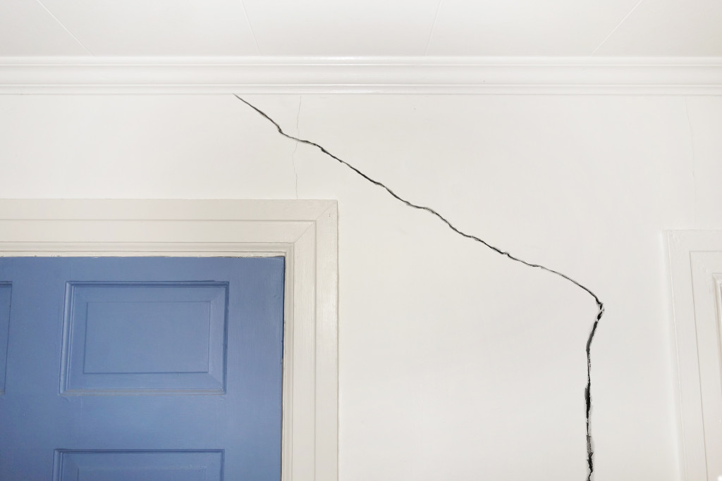 A crack in the wall of a house near a door, indicating foundation defects