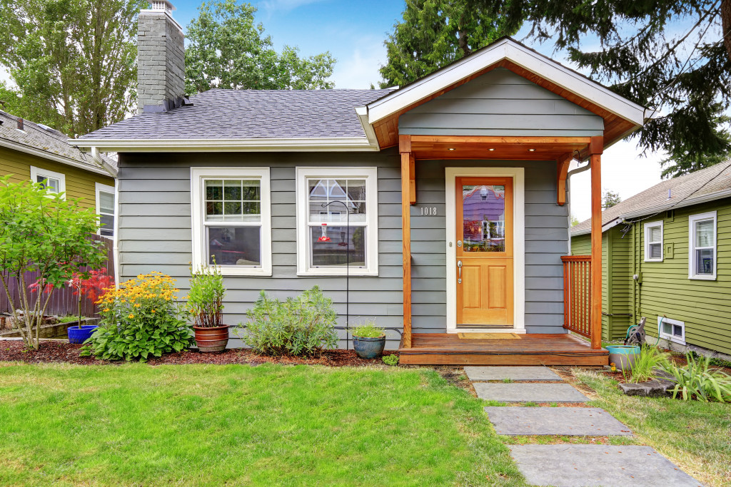 small gray house with plans in the front yard