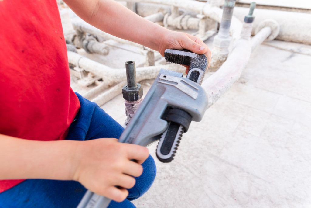 A man holding a plumbing wrench about to repair damage